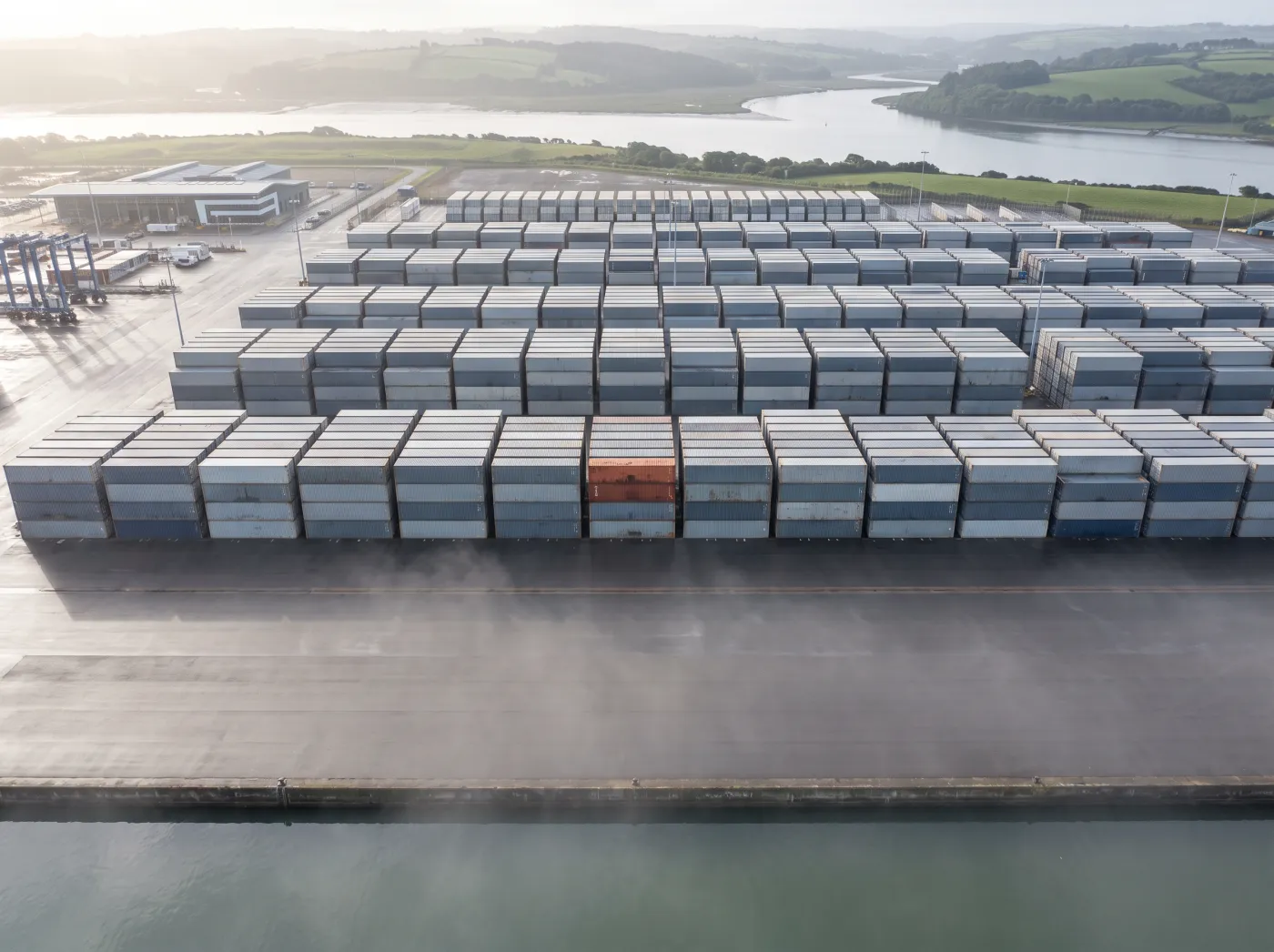 Containers in a precise grid seen from above, one orange container at the centre
